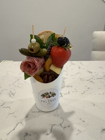A personal garden of cheese, salami, fruit, olives, pecans, and herbs.
